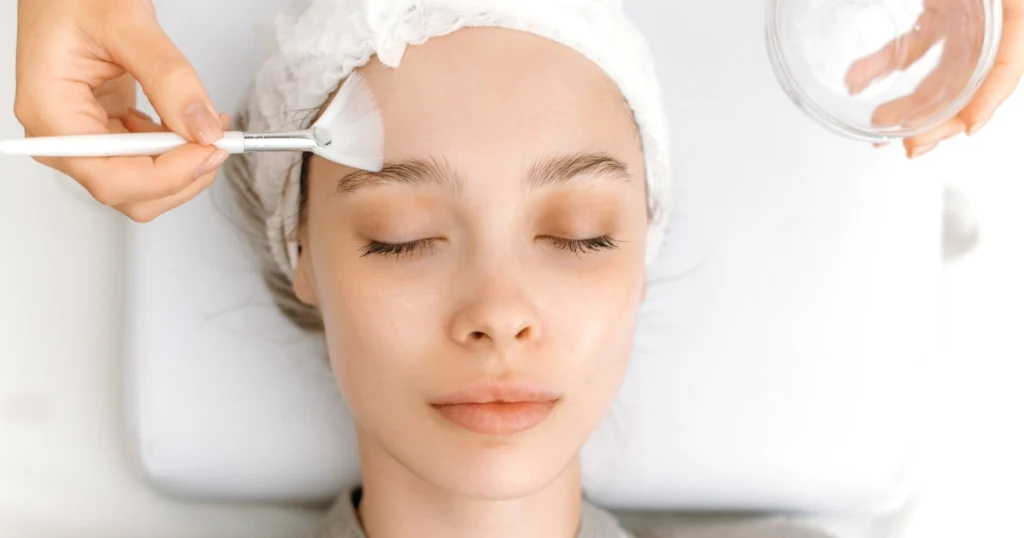 How Chemical Peels Treat Sagging Skin 1 Esthetician applying a chemical peels to a woman’s face using a brush during a professional facial skin treatment in Dallas