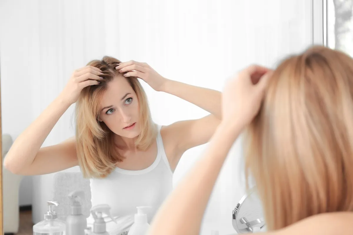 Woman styling hair in mirror at home