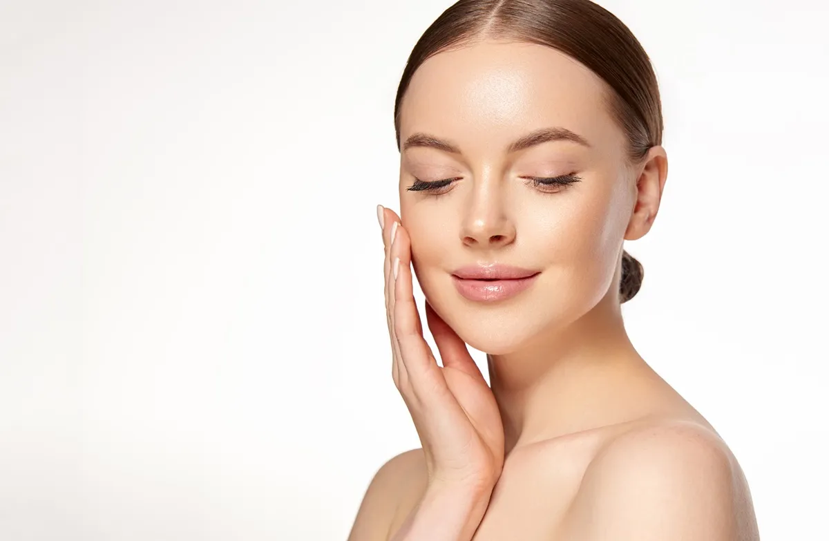 Woman touching cheek with radiant glowing skin