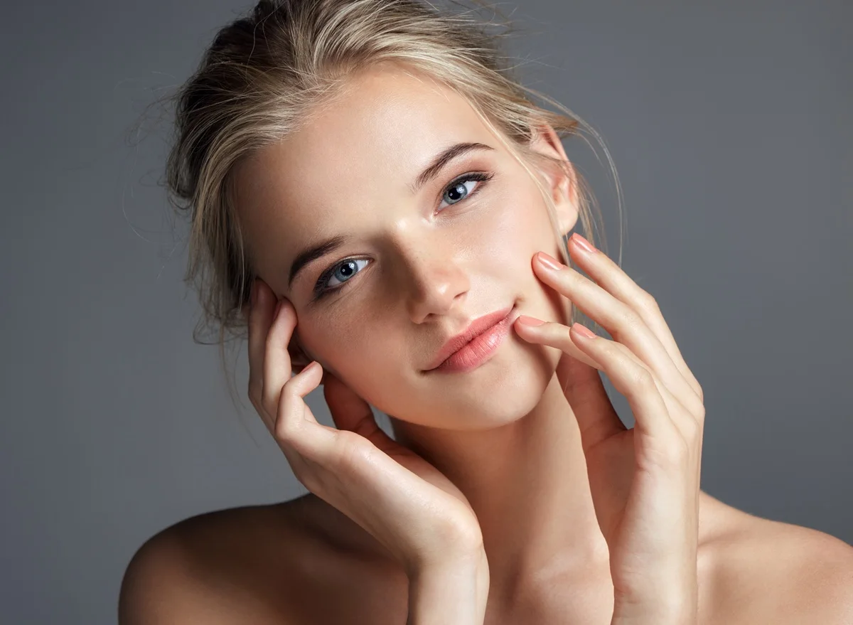 Young woman touching cheeks with radiant skin